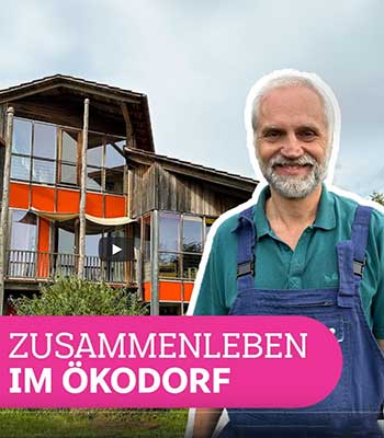 Jürgen steht vor dem Haus "Brunnenwiese". Unten im Bild steht "Zusammenleben im Ökodorf"